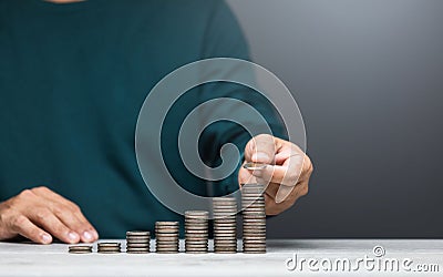 Man is stacking coins on a table, arranging them from smallest to largest. The image represents financial growth, savings, and Stock Photo