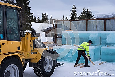 Man stacks cut ice block to build the Ice hotel in Jukkasjärvi in Sweden with a loader Editorial Stock Photo