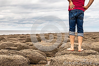 Man standing barefoot on the beach of stones on the seashore Stock Photo