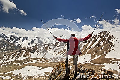 Man standing on a cliff in mountains with poles Stock Photo
