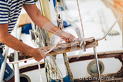 Man standing on the deck of his boat using a winch while out for a sail on a sunny afternoon Stock Photo