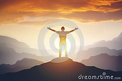 Man standing on edge of mountain feeling victorious with arms up in the air. Stock Photo