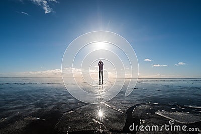 A man standing on frozen lake with sun and flare effects at winter Editorial Stock Photo