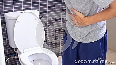 A man standing has diarrhea and severely toxic food. Man touch belly in the bathroom. Abdominal pain, Diarrhea,Colon cancer concep Stock Photo