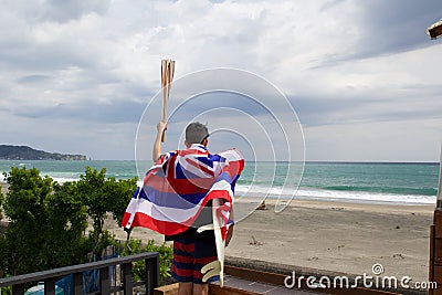 Man hold a torch used in large sporting event , with Hawaiian flag and surfboard. Stock Photo