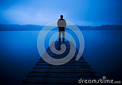 Man Standing on a Jetty by Tranquil Lake Concept Stock Photo