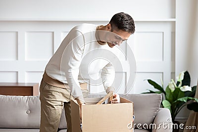 Man unboxing cardboard box with belongings relocated at new house Stock Photo