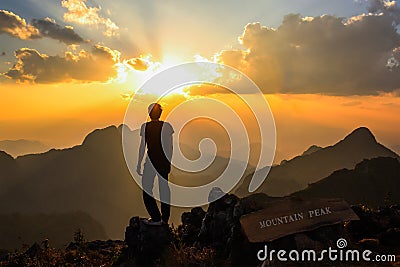 Man standing on mountain peak at sunset Stock Photo