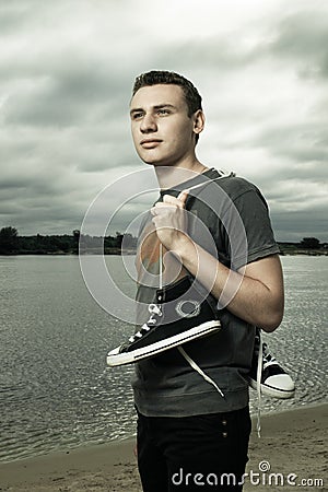 Man standing on the river bank with trainers Stock Photo