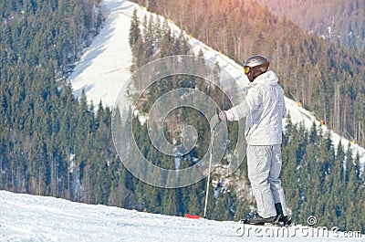 Man standing on skis on a snowy slope. Mountains in the background Stock Photo