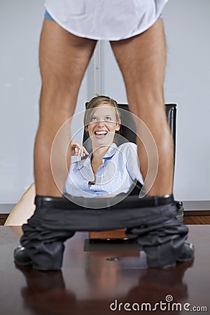 Man standing on table with trouser down, flirting with businesswoman in office Stock Photo