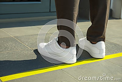 Man standing on taped floor marking for social distance outdoors. Coronavirus pandemic Stock Photo