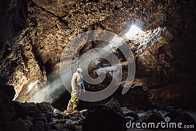 Man standing under the light in the mountain cave. Extreme adventure travel concep Stock Photo