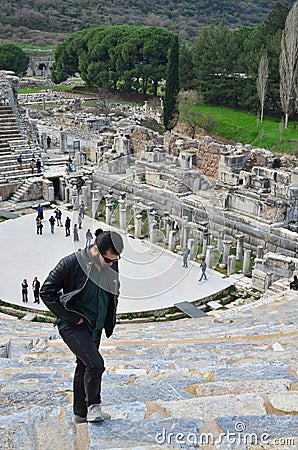 Man stands atop a set of weathered stone steps leading down to Ephesus Ancient Greek Theatre Editorial Stock Photo