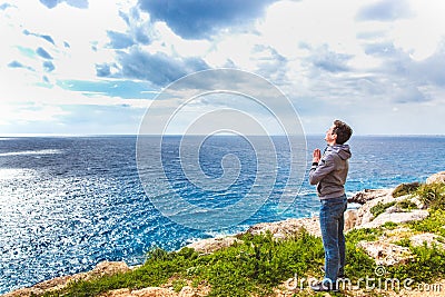 Man stands on the edge of the abyss and looks at the sea Stock Photo