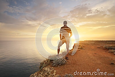 Man stands on the edge of the abyss and looks at the sea Stock Photo