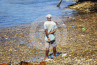 A man stands in the garbage at sea on Wasini island, Kenya. They are plastics in the Indian Ocean, Africa. Editorial Stock Photo