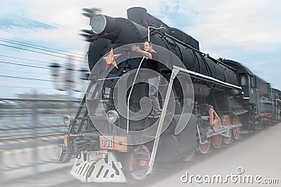 A man stands on a moving steam locomotive. The smoke from the engine of the train. The guy shows up on the railway. Retro Stock Photo