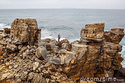 Man stands on a sea cliff, dark stormy sea on background Stock Photo