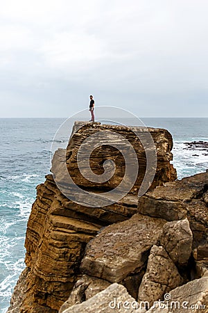 Man stands on a sea cliff, dark stormy sea on background Stock Photo