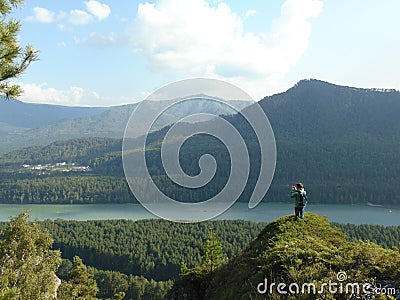 A man stands on top of a mountain and admires the view. Editorial Stock Photo