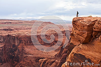 Man stands on top of a mountain. Hiker with backpack standing on a rock, enjoying valley view, Arizona Stock Photo