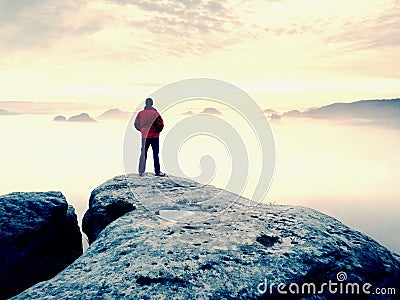 Man is staying on a top of a rock above clouds. Man on mountain. Stock Photo