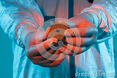 A man in sterile form holds a microprocessor, close-up. Microchip production technology, modern production, special microcircuit. Stock Photo