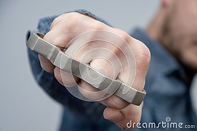 A man strikes a brass knuckles on a light background, a street gang of hooligans Stock Photo