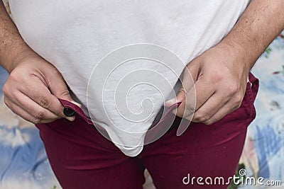 A man struggles to wear a pair shorts. A futile attempt. Weight gain concept, unable to fit into past clothes Stock Photo