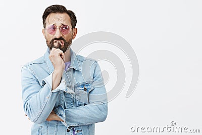 Man stuck with tough choice. Upset nervous and anxious handsome mature guy in sunglasses and denim jacket, biting lip Stock Photo