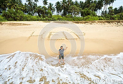 Man stuck on uninhabited island, inscription HELP on sand Stock Photo