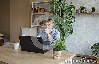 A man studies and takes notes with a laptop studying house plants, performs scientific work exploring botany Stock Photo