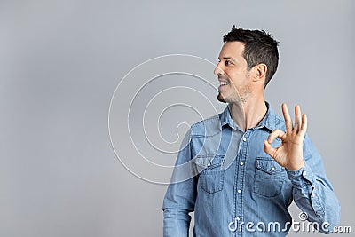 Man in studio in denim shirt doing okay sign with hand copy-space Stock Photo