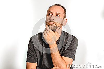 Man in studio, thoughtful hand resting on his chin, model expressions isolating white background Stock Photo