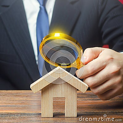 A man is studying a house through a magnifying glass. Fair value of real estate. Property valuation. Legal deal. Standards and Stock Photo