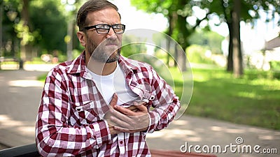 Man suffering chest pain, sitting outdoors, heart arrhythmia, ischemic disease Stock Photo