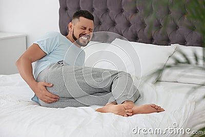 Man suffering from hemorrhoid on bed Stock Photo