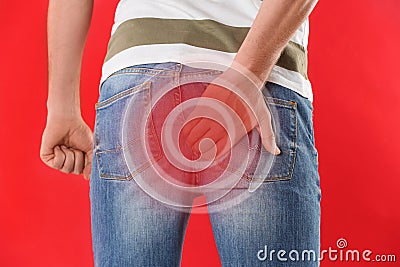 Man suffering from hemorrhoid on red background, closeup Stock Photo