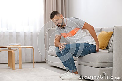 Man suffering from hemorrhoid on sofa Stock Photo