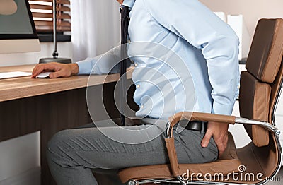 Man suffering from hemorrhoid at workplace in office Stock Photo