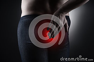 Man suffering from hemorrhoids, anal pain on black background Stock Photo