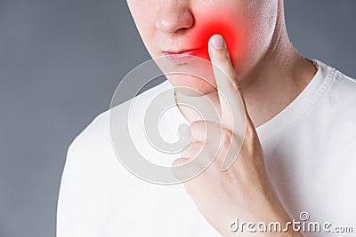 Man suffering from herpes virus on the lip, studio shot on gray background Stock Photo