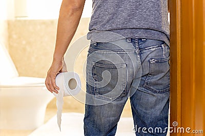 Man suffers from diarrhea holding toilet paper roll go to toilet. Stock Photo