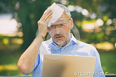 Man suffers from heat while working with laptop Stock Photo