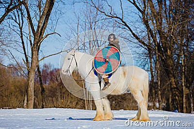 Man in suit of ancient viking riding big white horse Stock Photo