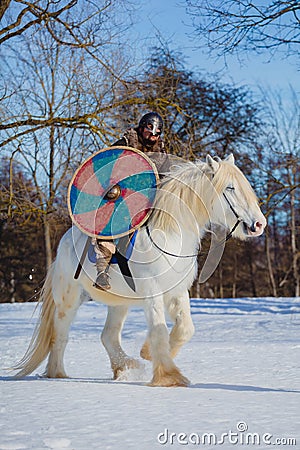 Man in suit of ancient warrior riding big white horse Stock Photo