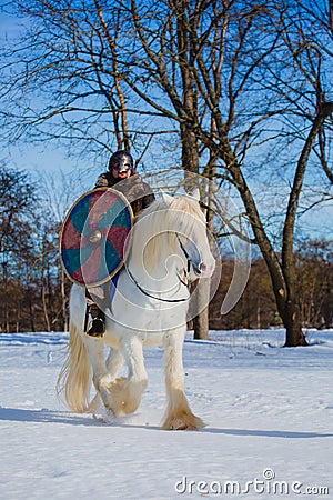 Man in suit of ancient warrior riding big white horse Stock Photo