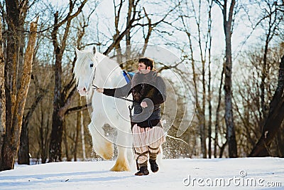 Man in suit of ancient warrior walking with the big white horse Stock Photo