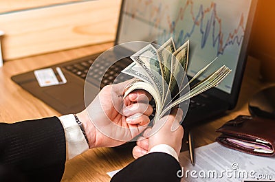 A man in a suit counts the money on a laptop with economic graphs. Investments in real estate. Business ideas, success story. Stock Photo